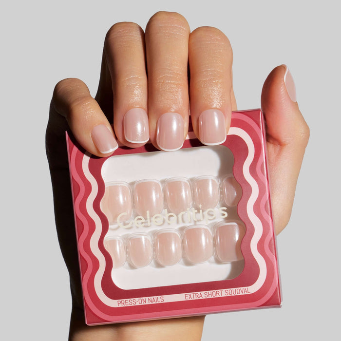 Hand holding Celebritips press-on nails in Micro French Glaze style with packaging displayed
