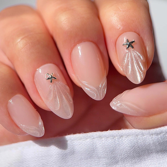 Princess By The Sea nail tips featuring nude pink almond nails with starfish and shell designs