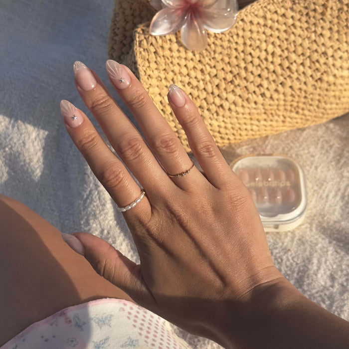Princess By The Sea press-on nails with pearl accents worn on model's hand in natural sunlight