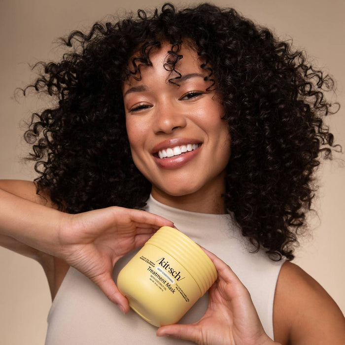 Woman with curly hair holding Kitsch coconut oil deep conditioning treatment mask