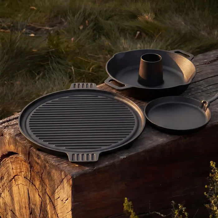 Pack cuisson en fonte Forest Grill avec plancha réversible, poêlon en fonte et support à volaille sur table en bois en extérieur