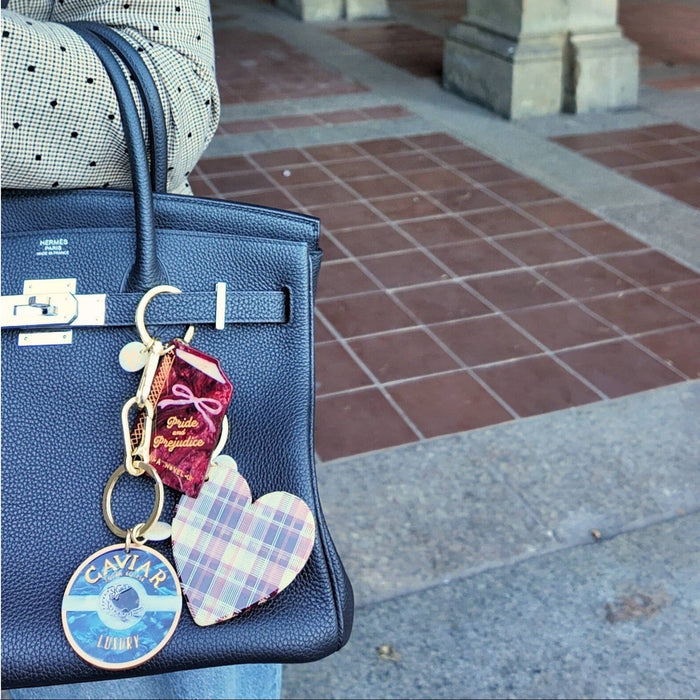 Blue Hermès Birkin bag with hand-painted caviar charm and colorful keychain accessories outdoors