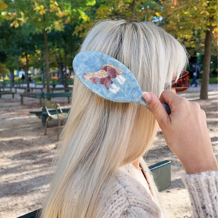 Hand-painted horse hair brush being held in park setting, demonstrating product use in natural outdoor environment