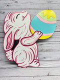 Unpainted wood cutout of a stylized chicken with a bow and flower-patterned egg, featuring etched lines for DIY painting.